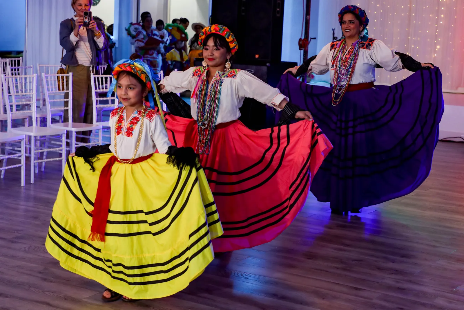Yellow, pink, and purple skirts with dark ribbon bands at Oaxaca en Utah’s Fashion Show 2025