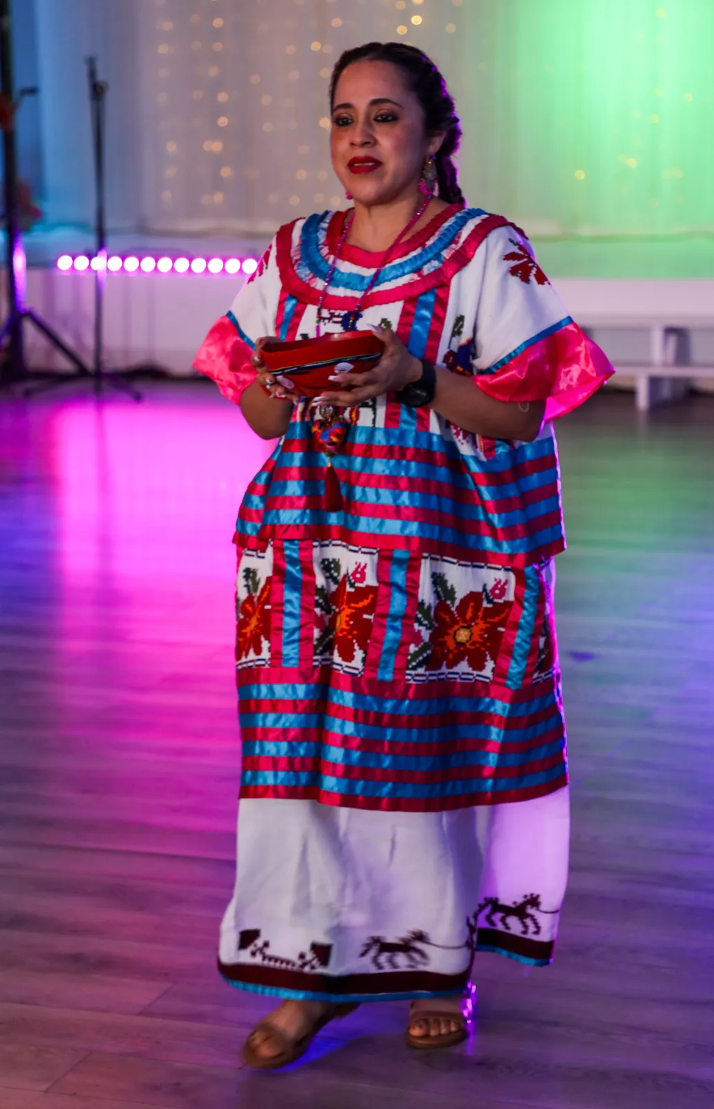 Huautla huipil with floral embroidery and bright pink-and-blue horizontal bands at Oaxaca en Utah’s Fashion Show 2025