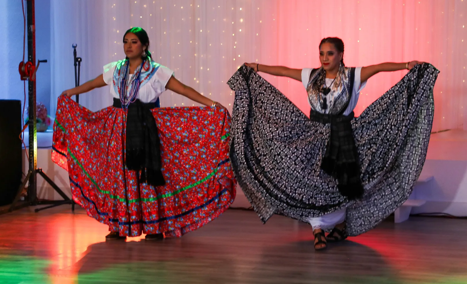 Two Jarabe Mixteco clothing presentations: red floral and black-and-white skirts at Oaxaca en Utah’s Fashion Show 2025