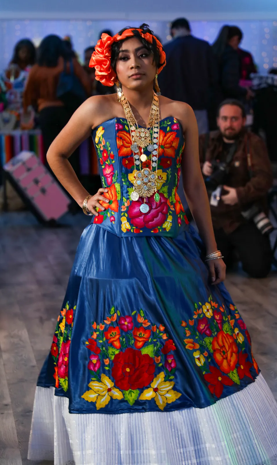 Blue floral embroidered quinceañera outfit with a full skirt and white lace hem at Oaxaca en Utah’s Fashion Show 2025