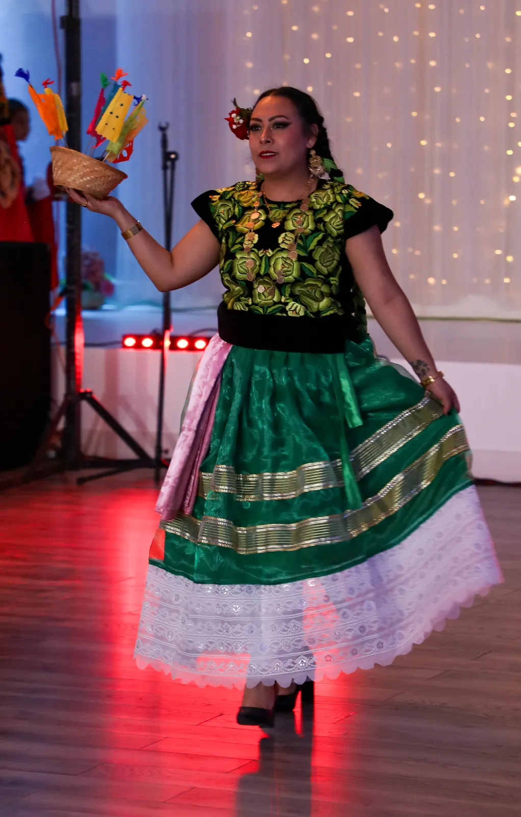 Green rabona skirt with gold-colored bands and white lace, paired with an embroidered huipil at Oaxaca en Utah’s Fashion Show 2025