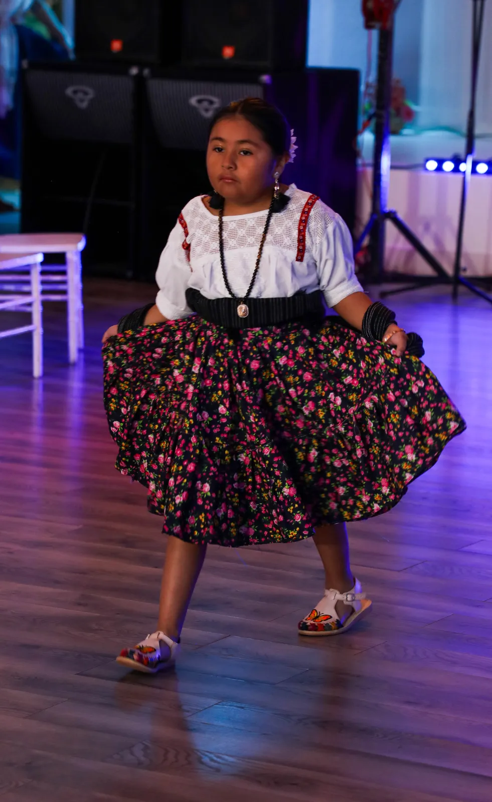 White embroidered blouse and short floral skirt held open at Oaxaca en Utah’s Fashion Show 2025