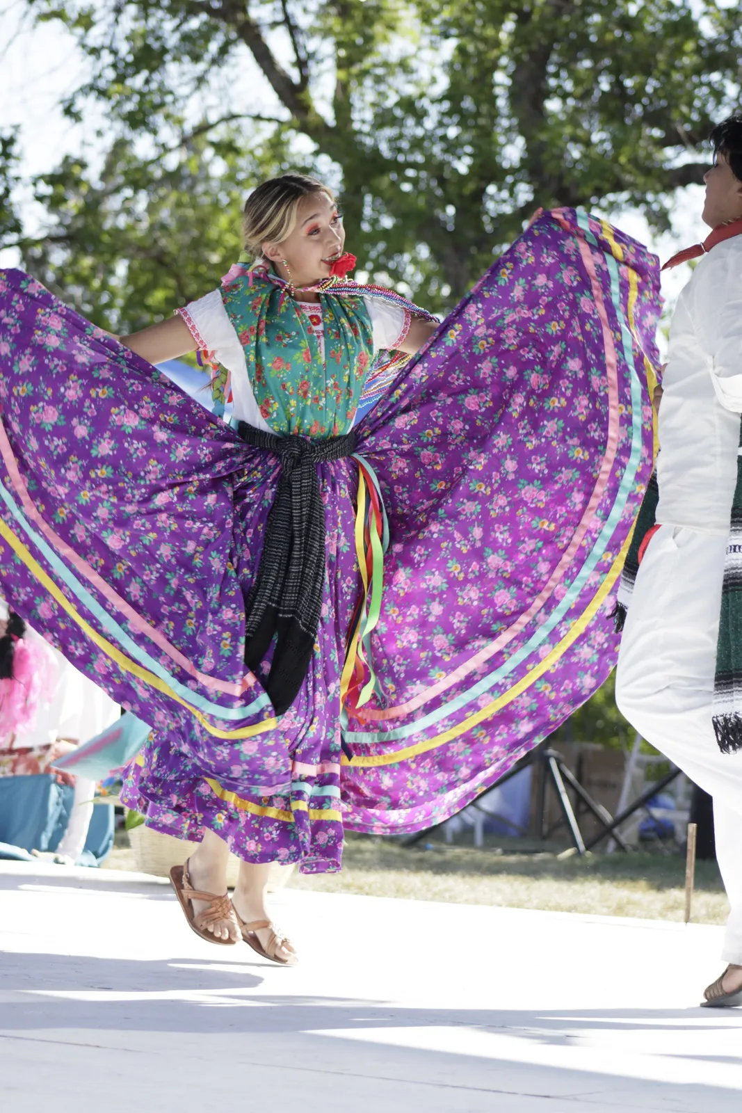 A Jarabe Mixteco dancer opens a purple floral skirt at La Guelaguetza 2026