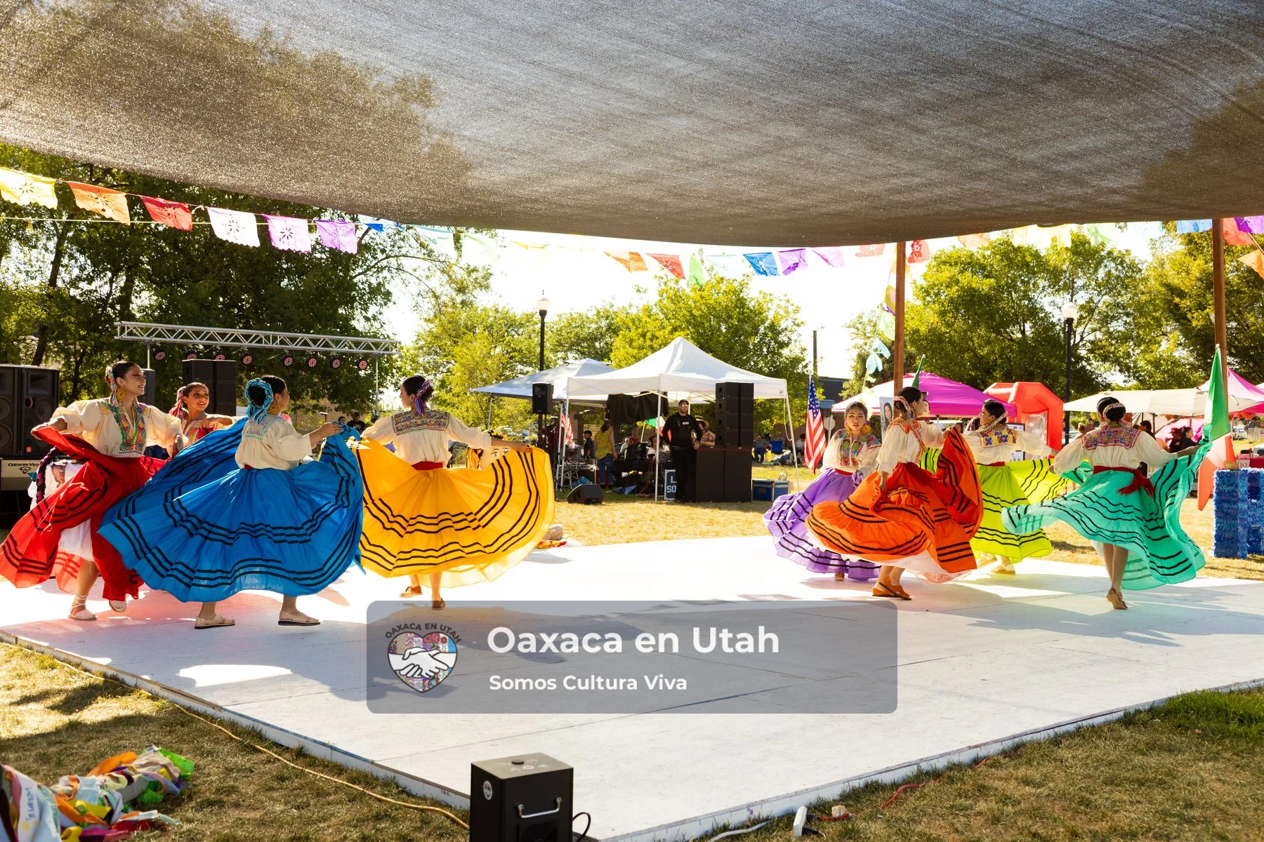Dancers lift bright skirts across the festival stage at La Guelaguetza 2026