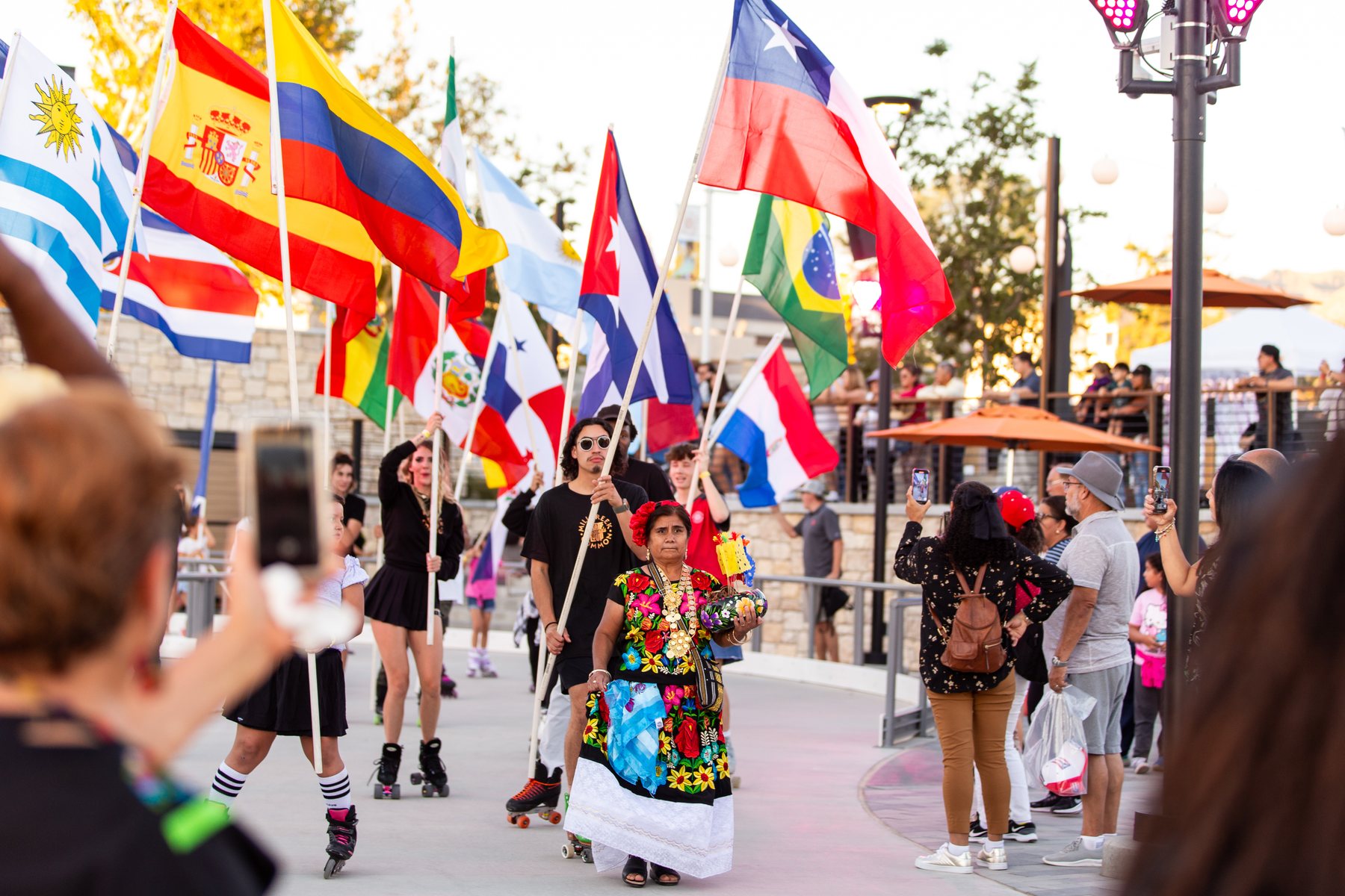 Participantes caminan entre una exhibición de banderas latinoamericanas en Mi Gente!