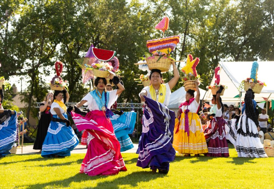 Young Oaxaca en Utah dancers performing in traditional white dresses at La Guelaguetza