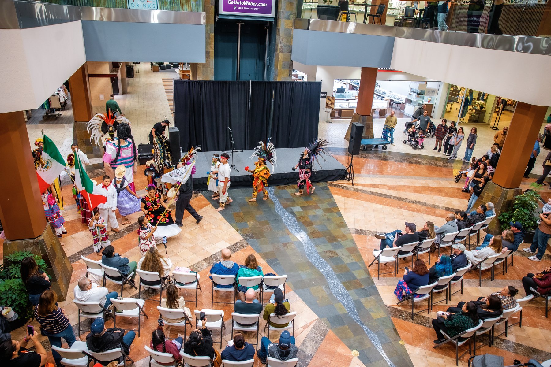 Una amplia vista desde arriba muestra al público y a los artistas alrededor del escenario del centro comercial
