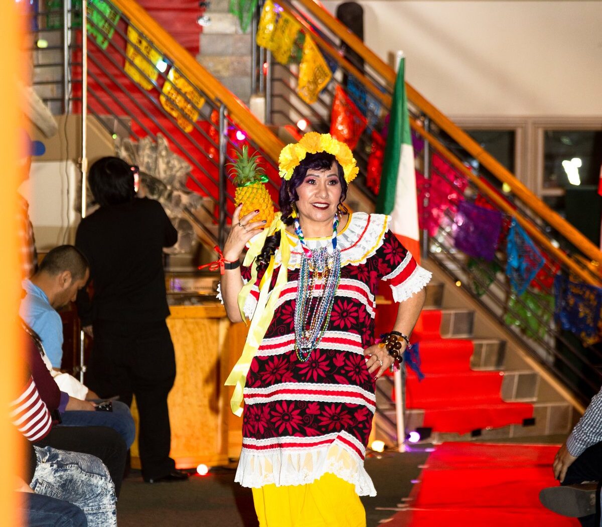Fotografía representativa temporal del Desfile de Moda 2026 con una participante en vestimenta tradicional que lleva una piña en la pasarela; será reemplazada por una fotografía del evento de 2024