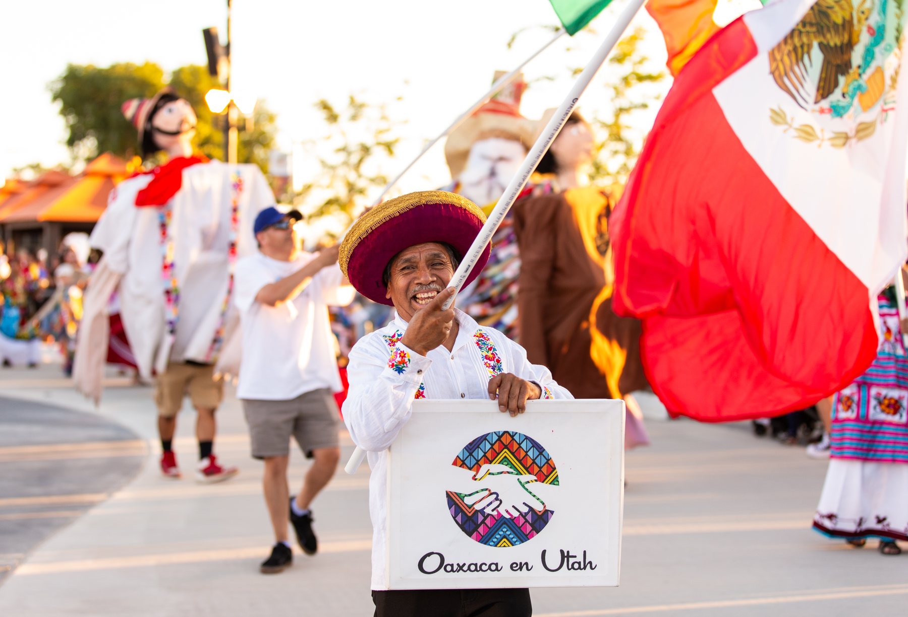 Un participante lleva una gran bandera de México y un letrero de Oaxaca en Utah
