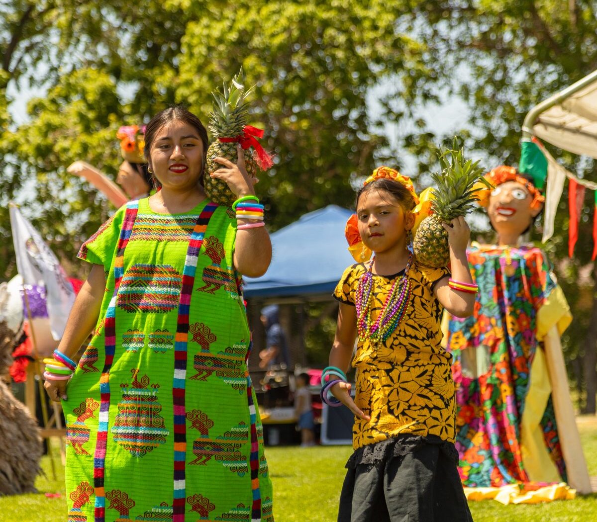 Temporary representative photograph from La Guelaguetza 2025 showing two participants carrying pineapples outdoors; a 2024 event photograph will replace it