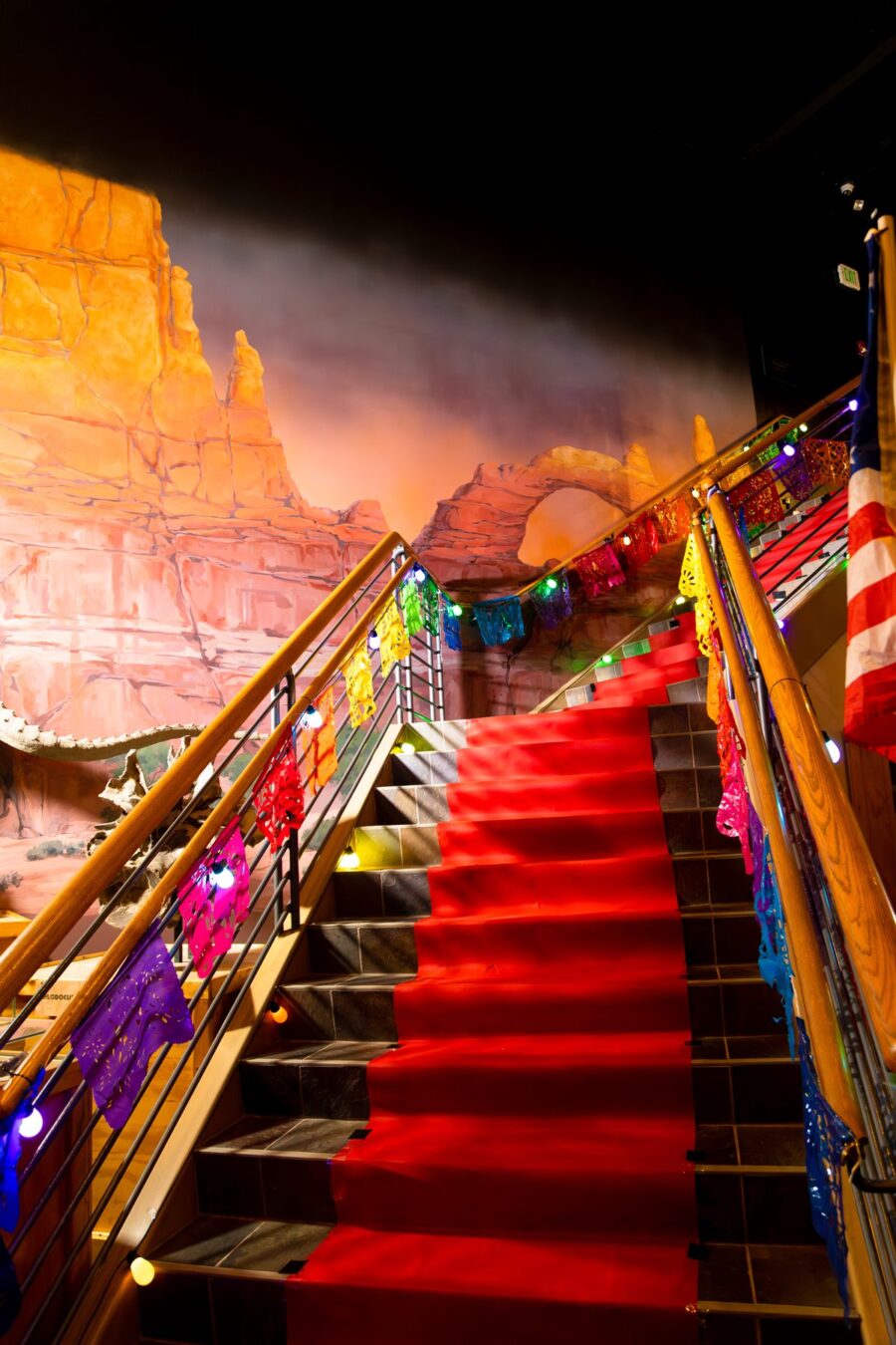Una alfombra roja y papel picado multicolor decoran la escalera dentro de Ogden Dinosaur Park