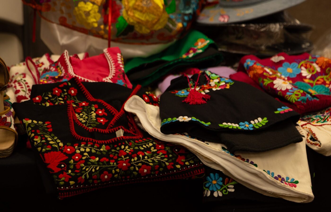 Prendas bordadas a mano de diversos colores reunidas para la exhibición textil del Desfile de Moda 2026