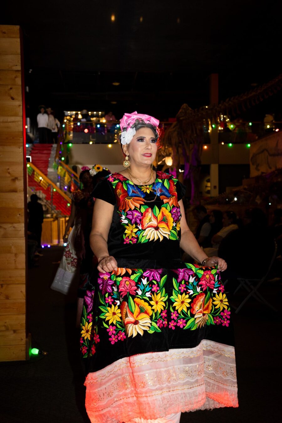 Una mujer presenta un vestido negro cubierto de vivos bordados florales en la pasarela del Desfile de Moda 2026