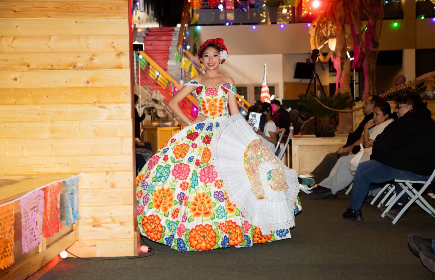 Una modelo sonríe en la pasarela con un amplio vestido blanco decorado con grandes flores multicolor