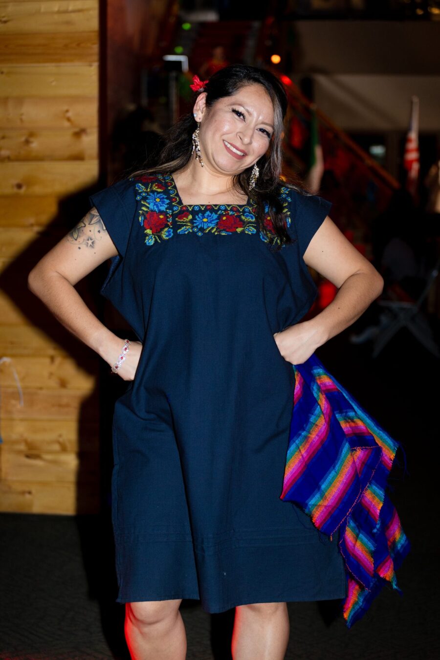 Una modelo posa en la pasarela con un vestido azul marino bordado y un textil tejido multicolor