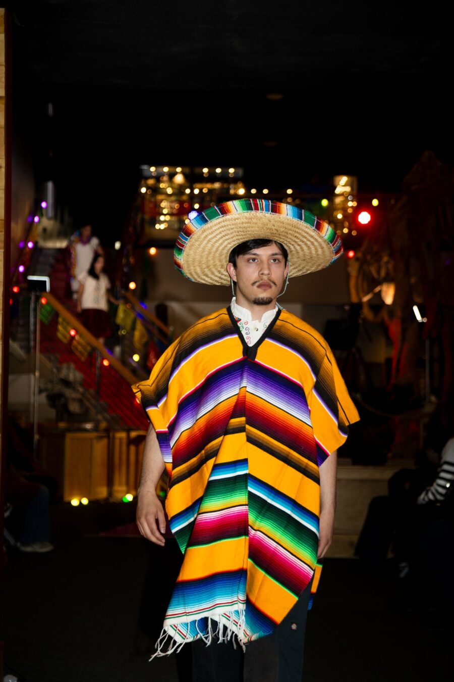 Un hombre presenta un sarape amarillo de rayas multicolor y un sombrero tejido en la pasarela
