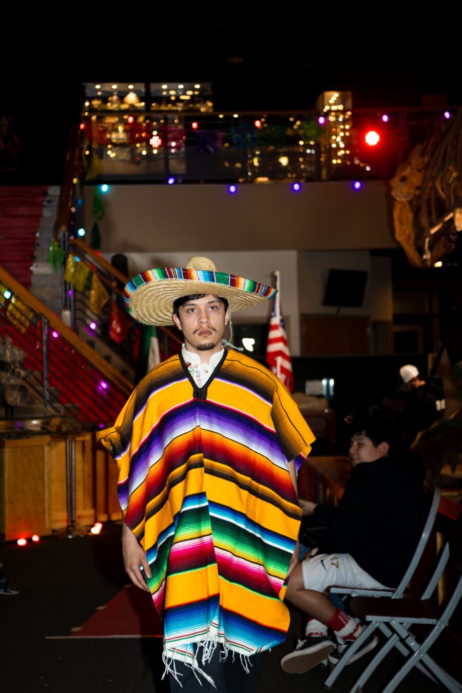 Un modelo camina por la pasarela con un sarape de rayas brillantes y sombrero de ala