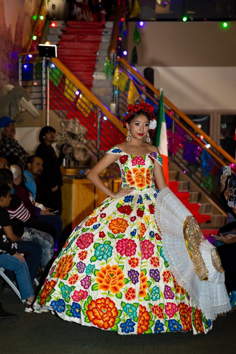 Una modelo camina por la pasarela con un amplio vestido blanco cubierto de grandes flores coloridas