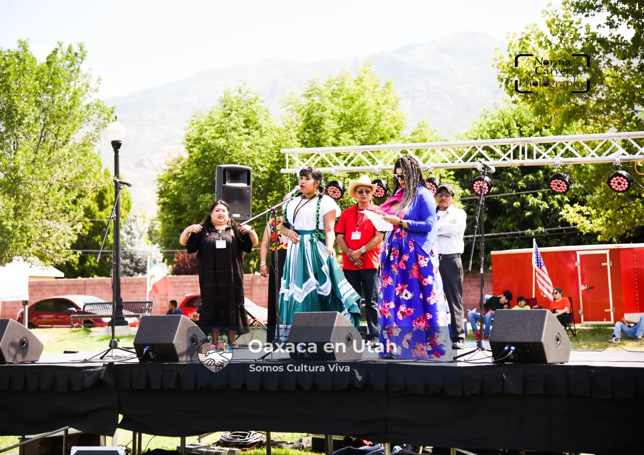 Presentadoras y participantes de Oaxaca en Utah están en el escenario exterior del festival