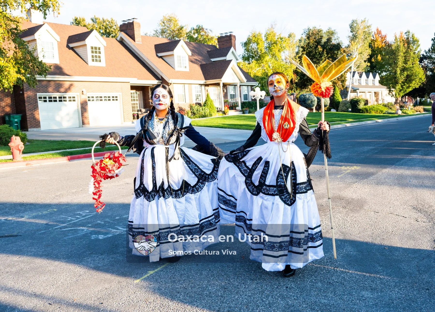 Two participants in black and white dresses stand together on a residential street