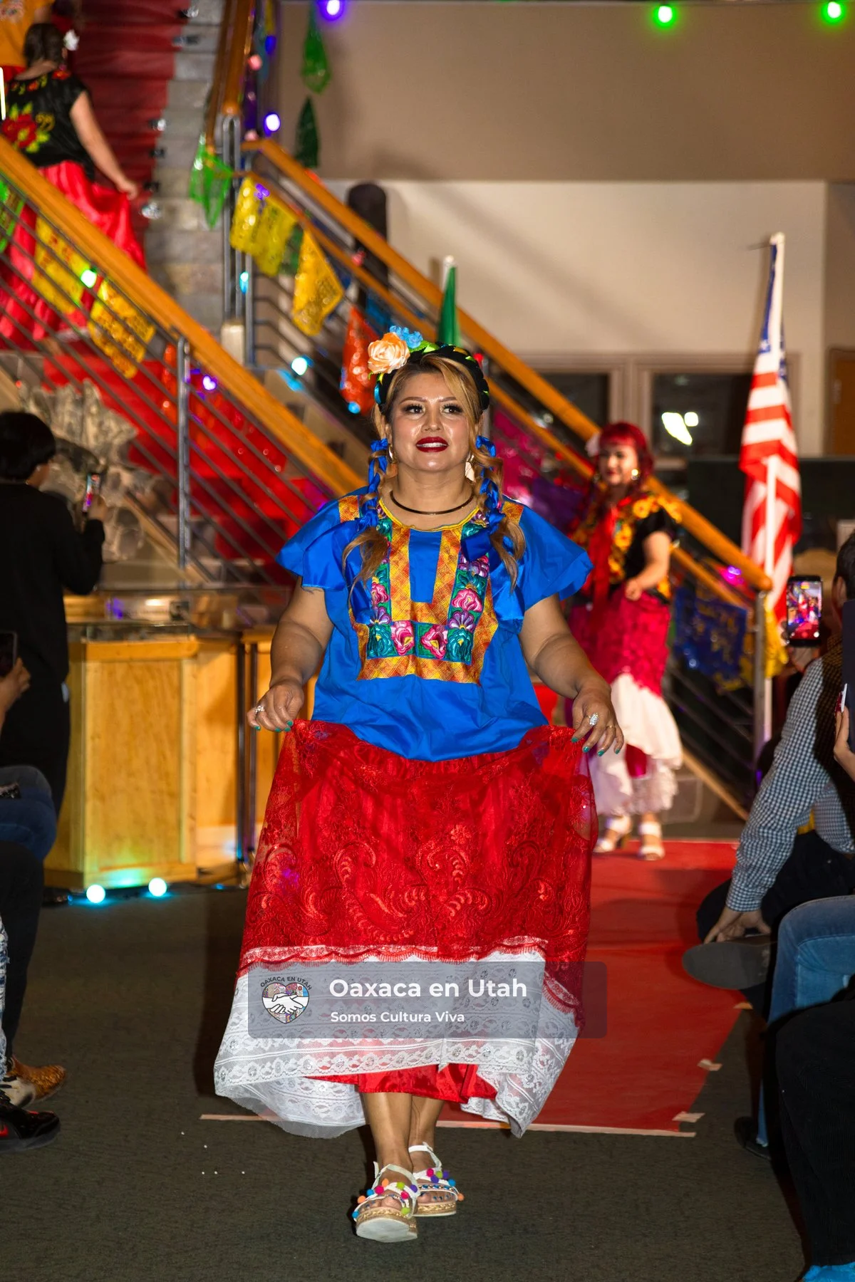 Una participante luce una blusa azul bordada y una falda roja en el Desfile de Moda 2026