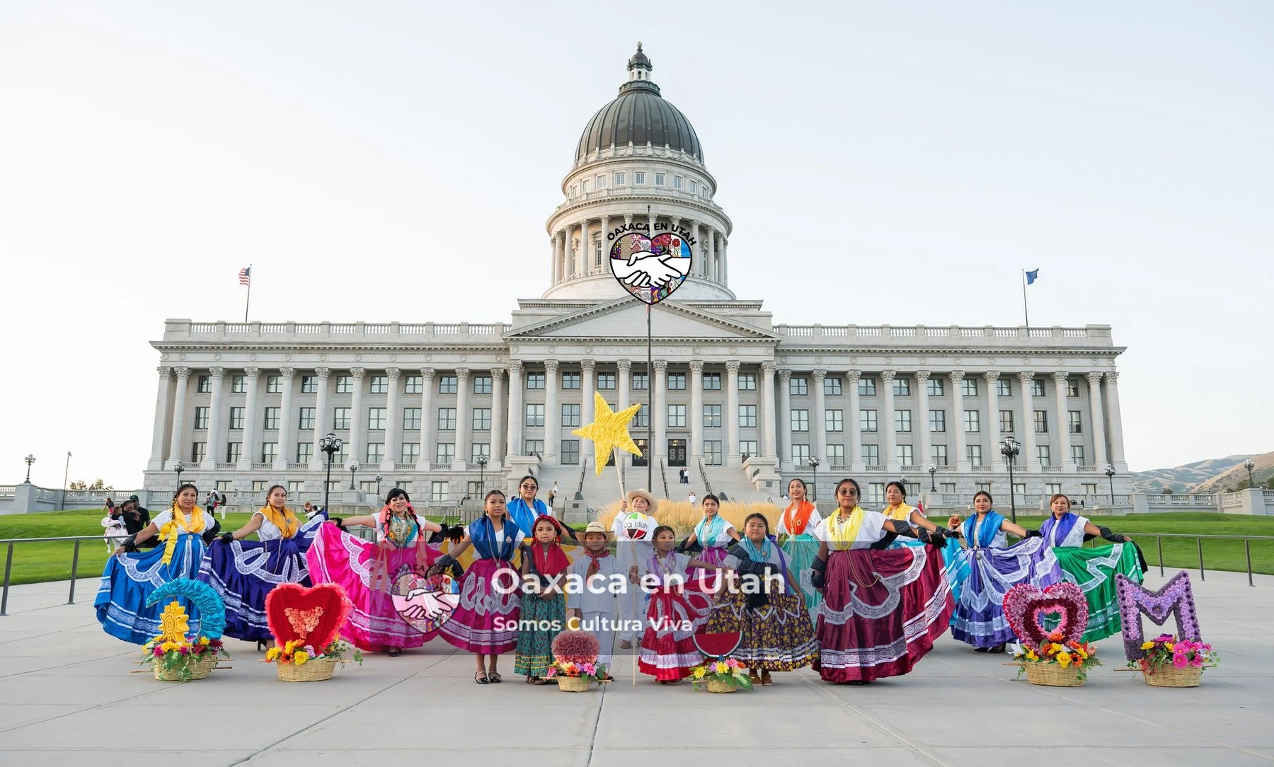 A large group in colorful clothing poses in front of the Utah State Capitol