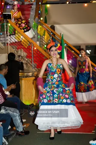 A participant walks the runway in a blue floral bodice and white skirt
