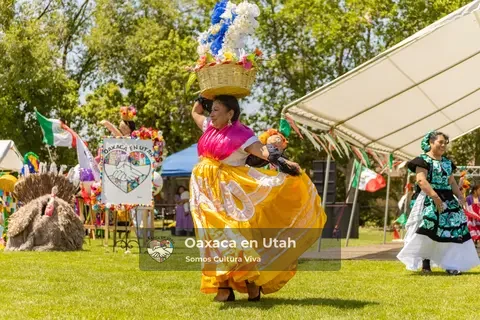 A participant in a bright yellow skirt moves across the grass near the stage
