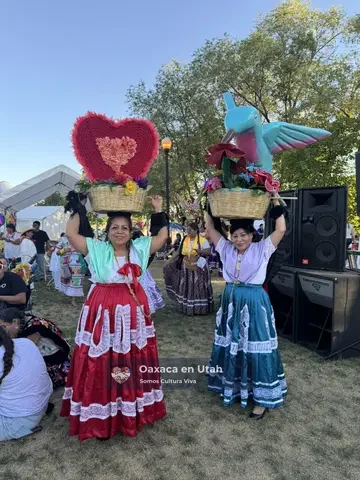 Two Chinas Oaxaqueñas hold decorated floral baskets at La Guelaguetza 2026