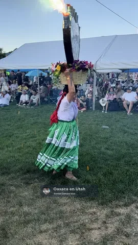 Una bailarina con falda verde lleva una canasta decorada con fuegos artificiales durante La Guelaguetza 2026