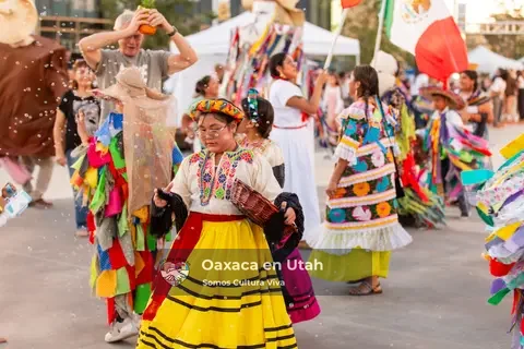 A participant in a yellow skirt carries a basket while a ribbon-covered performer passes nearby